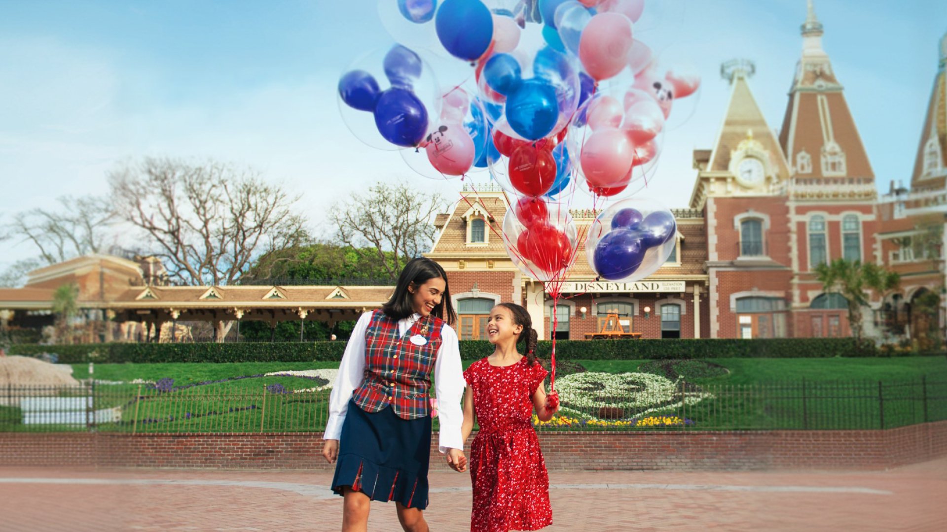 Mother and daughter with balloons at the entrance of Disneyland Resort