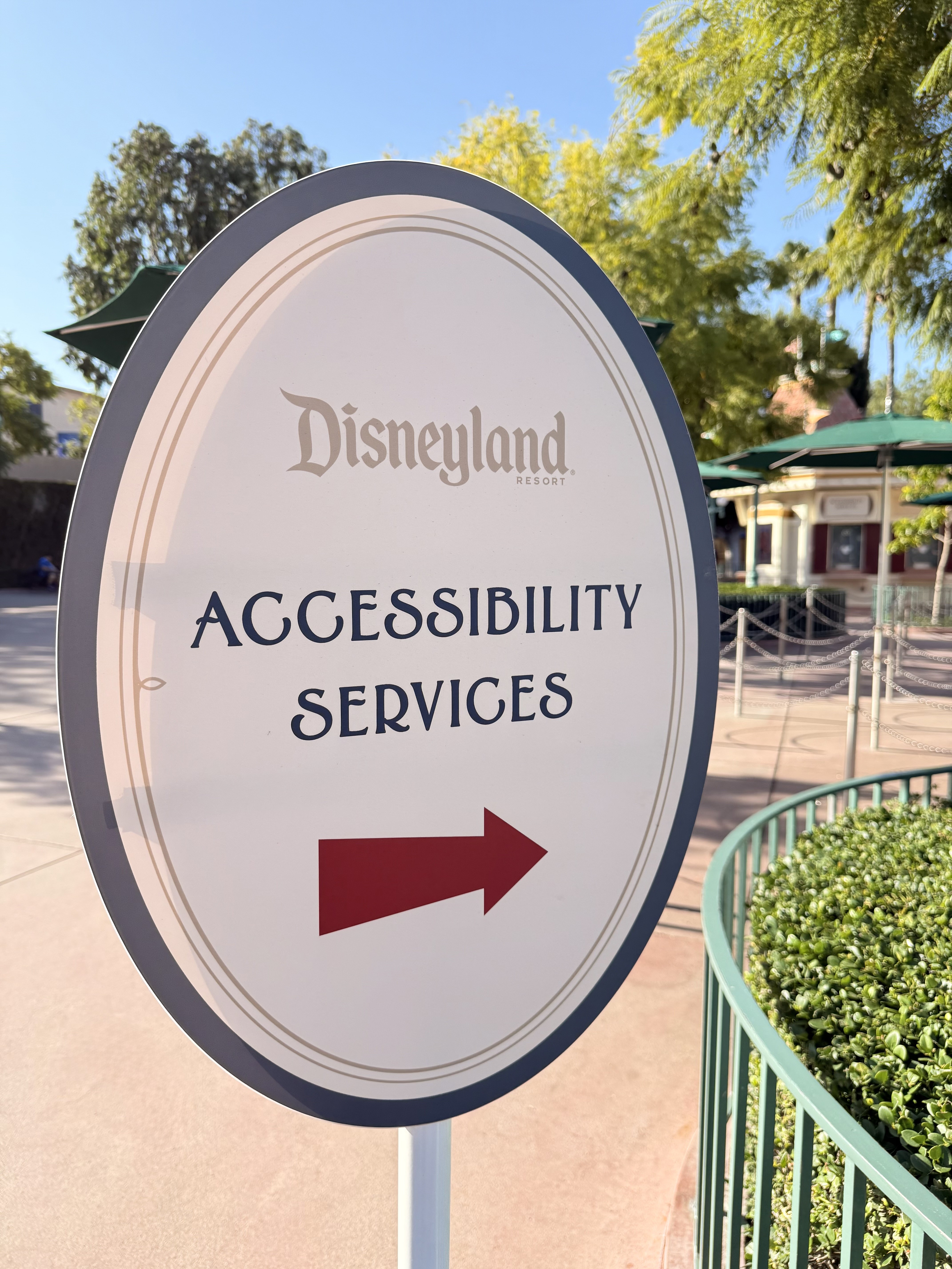 Disneyland Accessibility Services directional sign in a garden setting